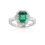 Emerald engagement ring with diamonds in the shape of tapered baguettes as side stones and a diamond halo.